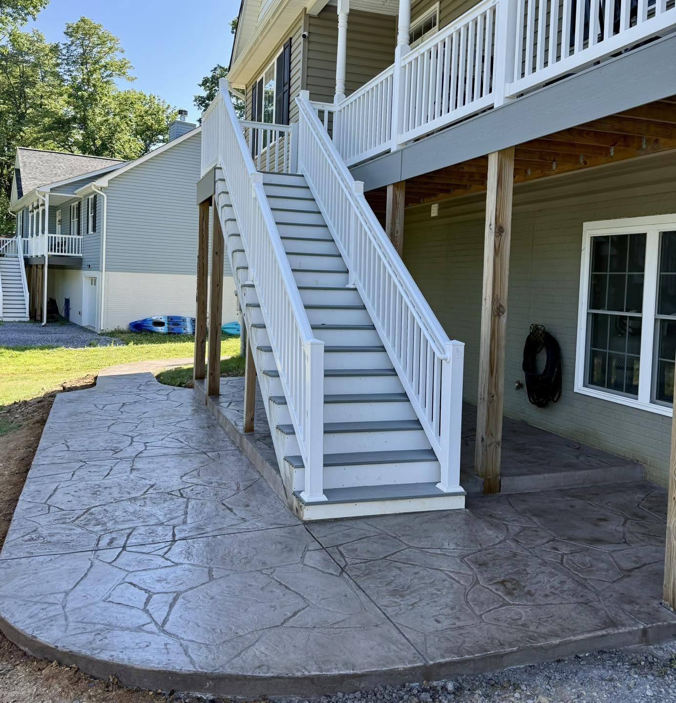 Stamped concrete patio under a rear deck with white stairs in Winchester VA