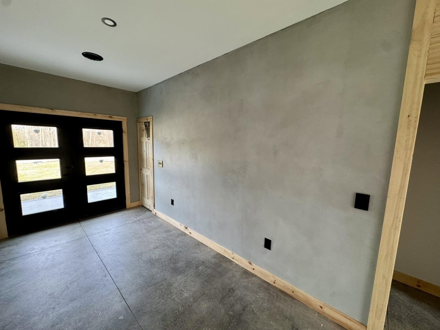 Microcement feature wall in a room with black glass doors in Winchester VA